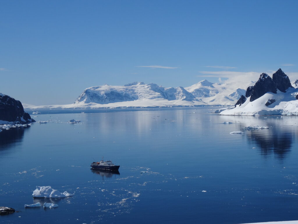 Antarctica Isn’t What You Think: How to Plan Your Trip 2 How to plan a trip to antarctica: a boat in the water with icebergs in the background
